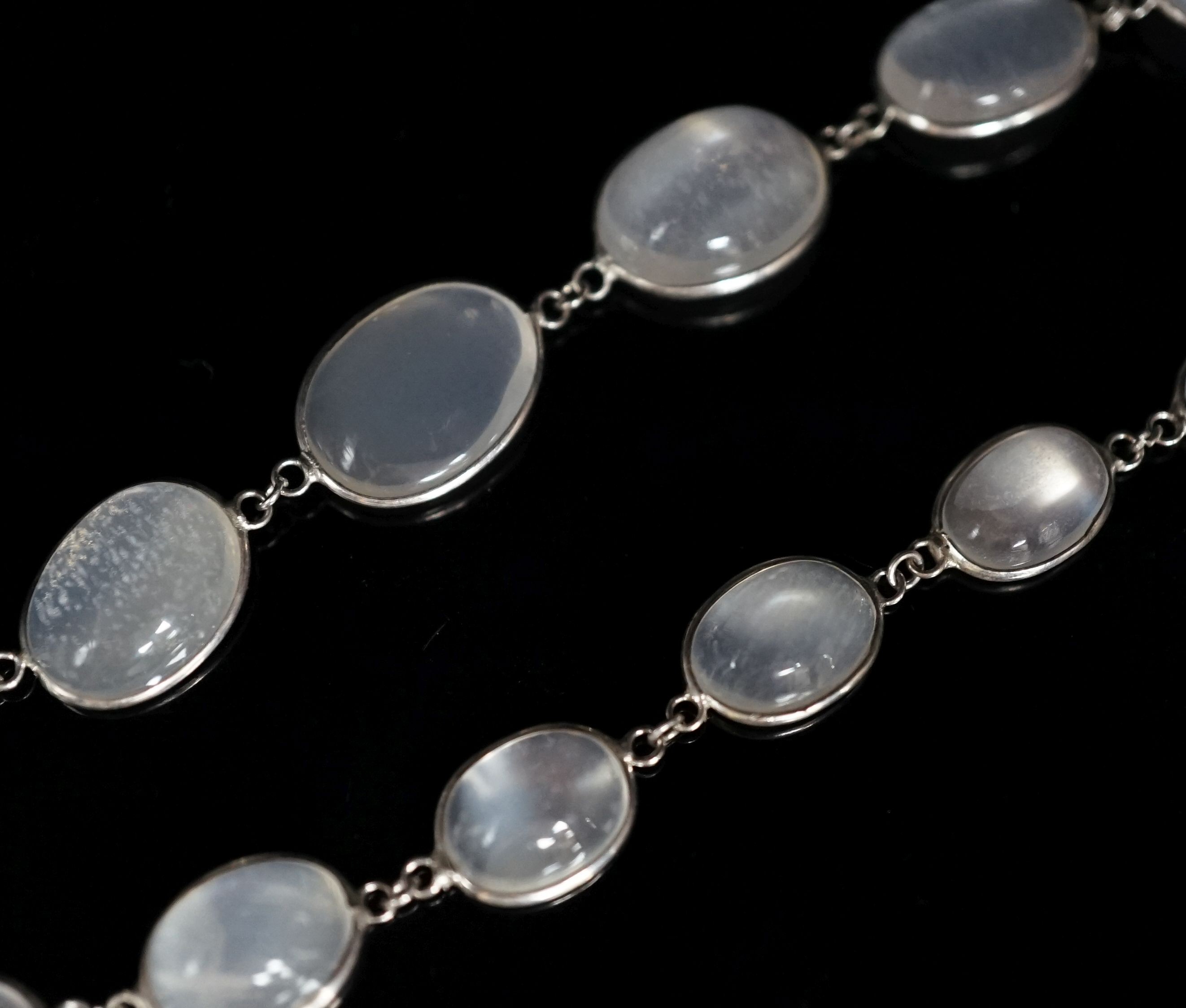 A modern (1980's) white metal and graduated moonstone set spectacle necklace, 69cm.